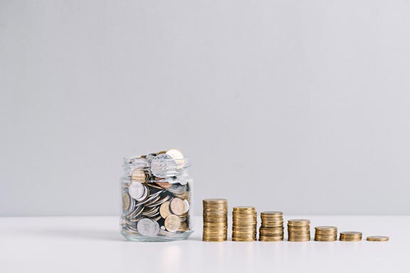 jar filled with coins and stairs of coins beside it